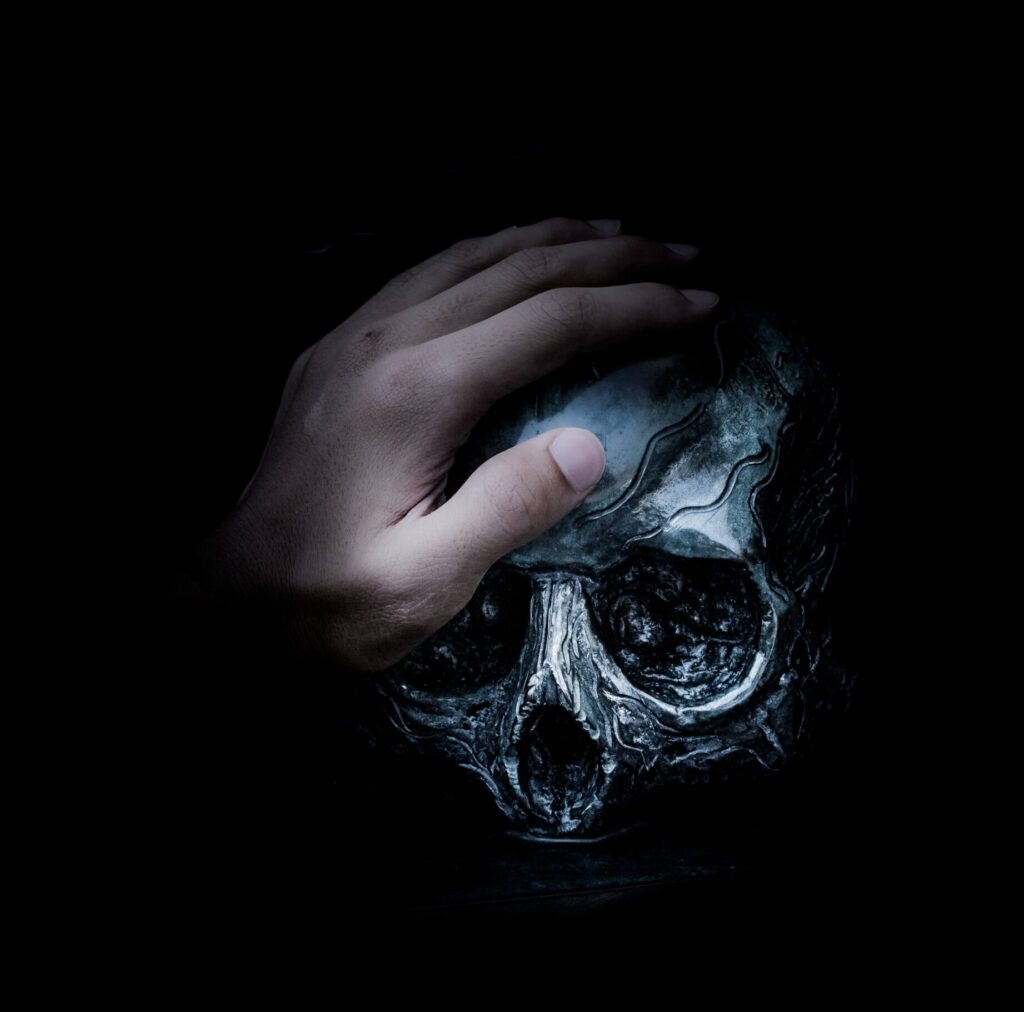 Dark urban fantasy book hand resting on silver skull giving dark vibes and atmosphere for supernatural thriller.